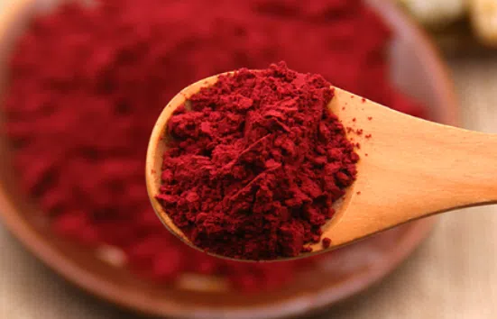 Red beet powder in a wooden spoon.