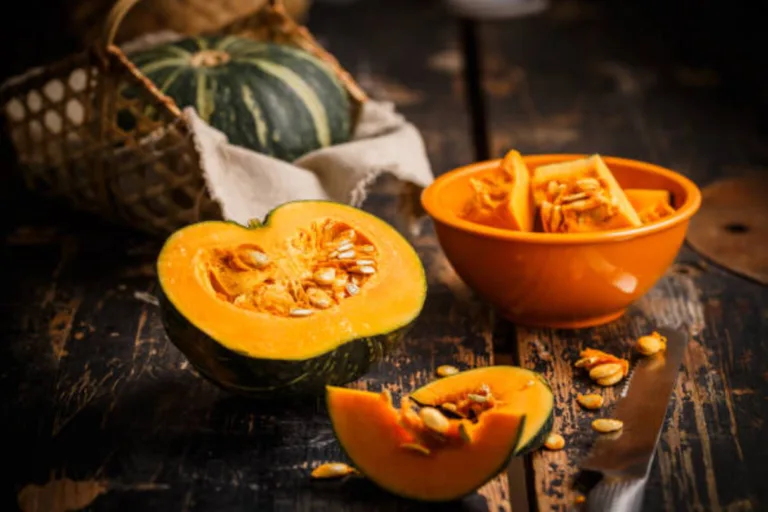 A pumpkin is cut in half and sitting on a wooden table.