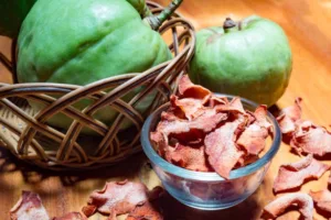 A bowl of dried guava fruit on a wooden table.