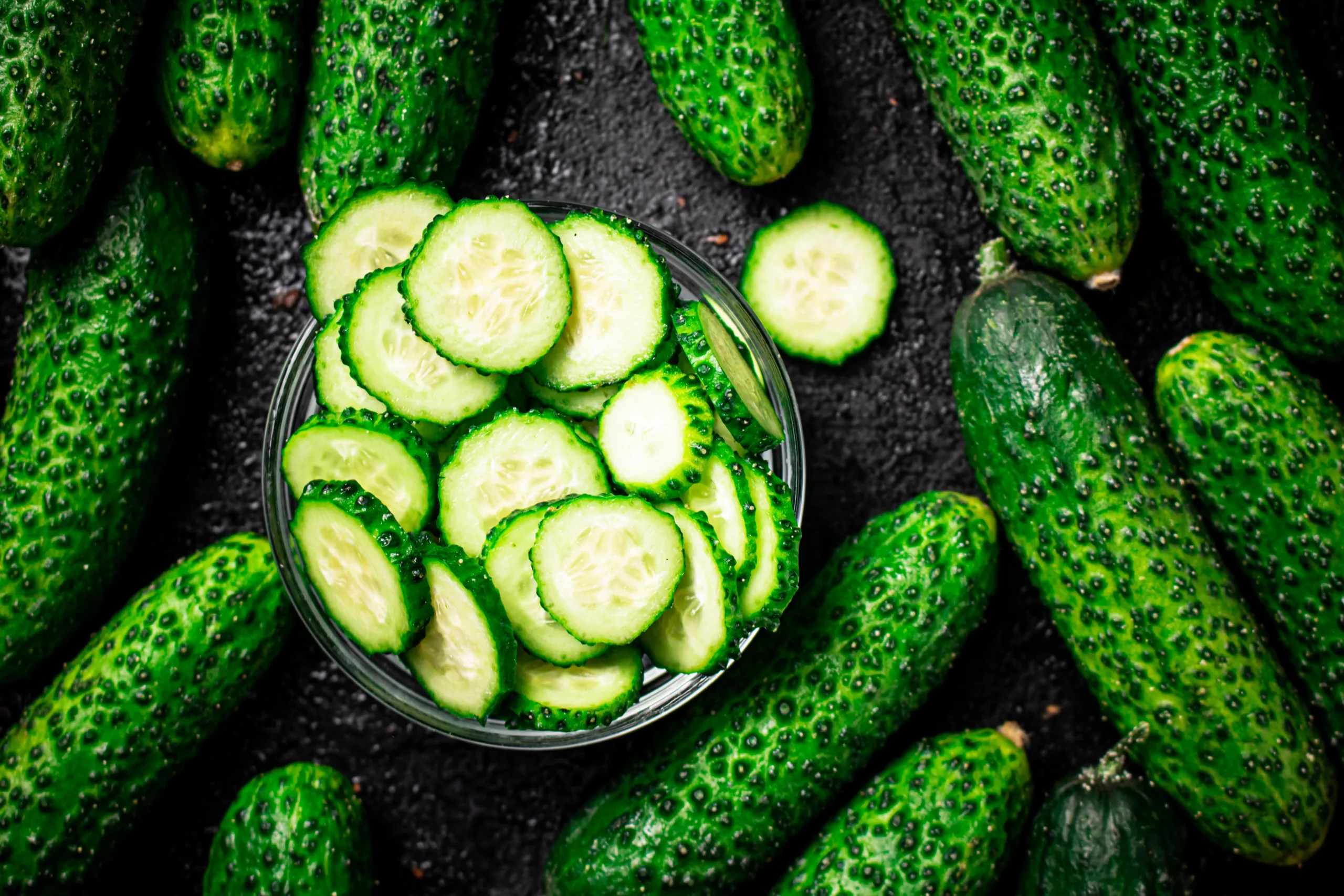 "A close-up image of a sliced cucumber and cucumber slices on a white background."