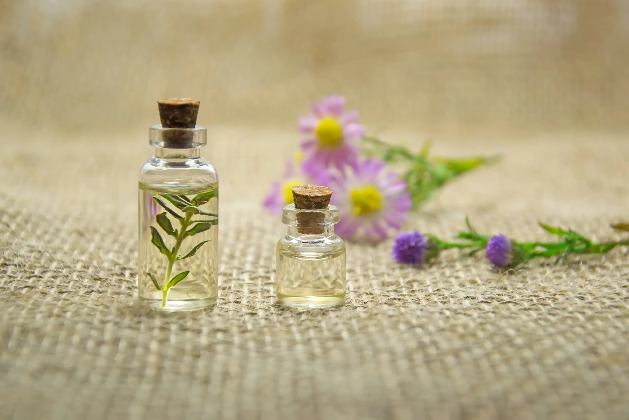 Two small bottles of essential oils on a burlap cloth, Personal care ingredients.