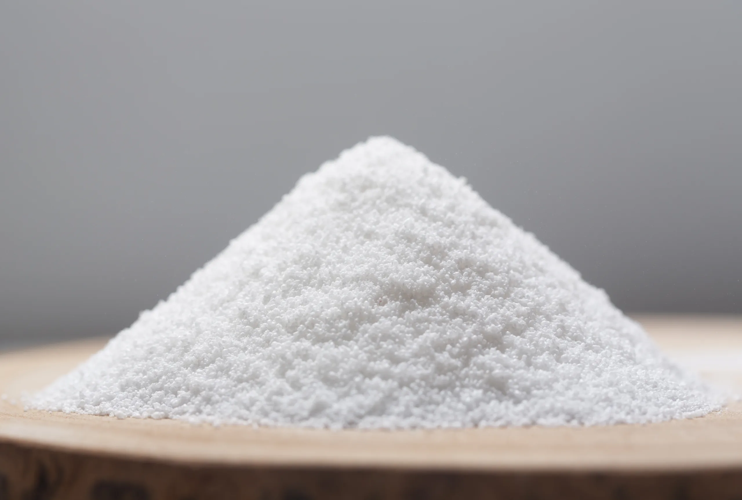 White crystalline aspartame powder, a low-calorie sweetener used as a sugar substitute in food and drinks.