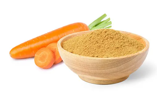 A bowl of carrot superfood powder on a wooden table.