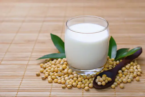 A jar of soybean peptide powder surrounded by soybeans.