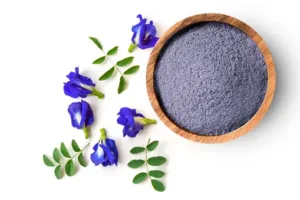 A bowl with blue powder and flowers on a white background.