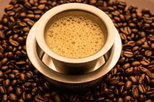 A cup of coffee sitting on top of coffee beans.