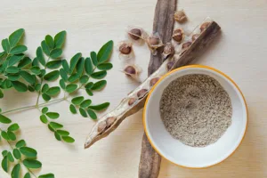 A bowl of powder and leaves on a wooden table.