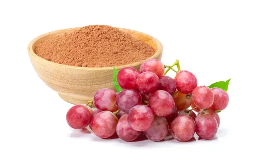 A bowl of grapes and a bowl of cocoa powder.