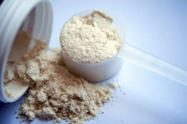 A scoop of protein powder next to a scoop of powder.