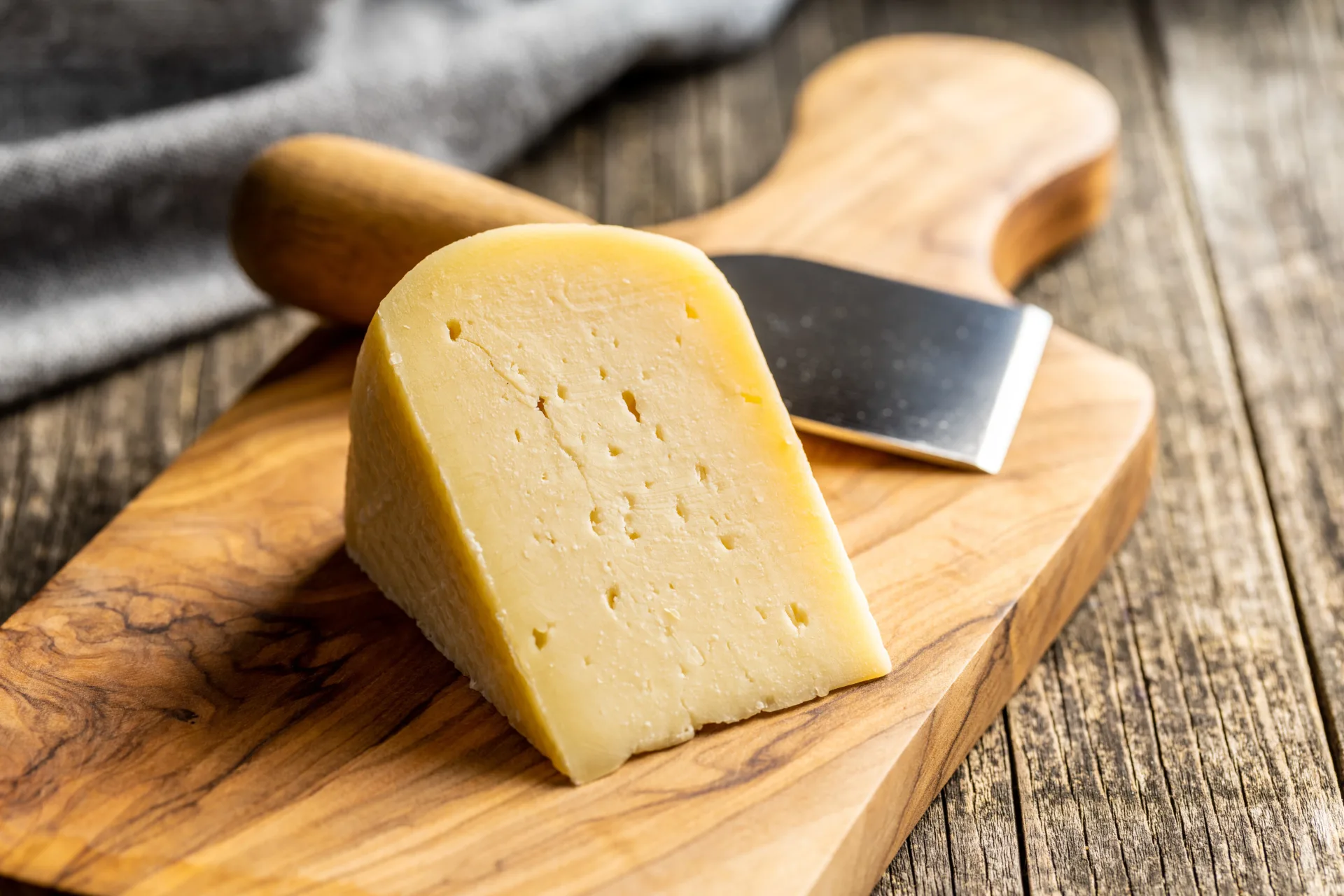Cheese wedge on wooden board with knife