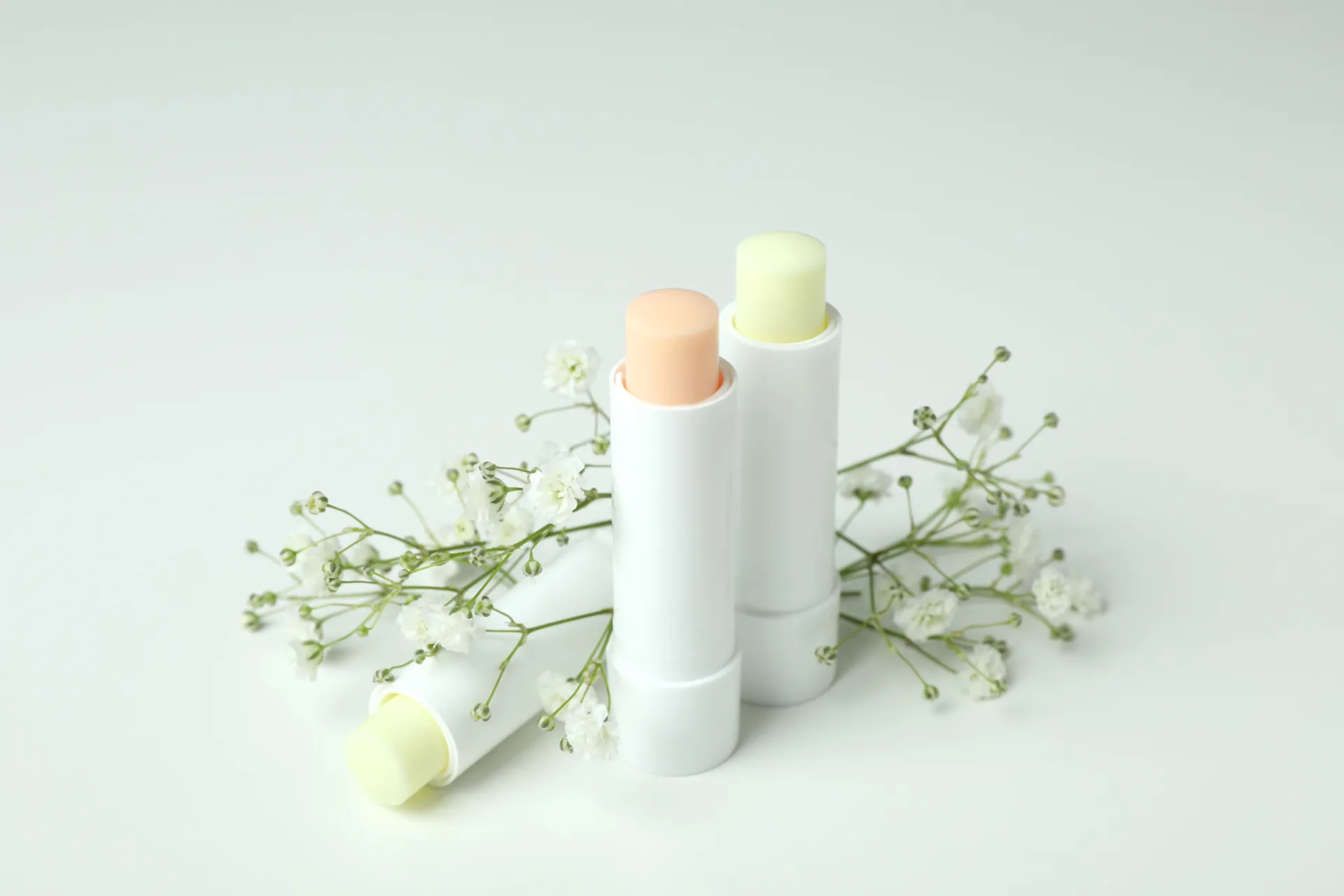 Natural lip balms with white flowers on white background