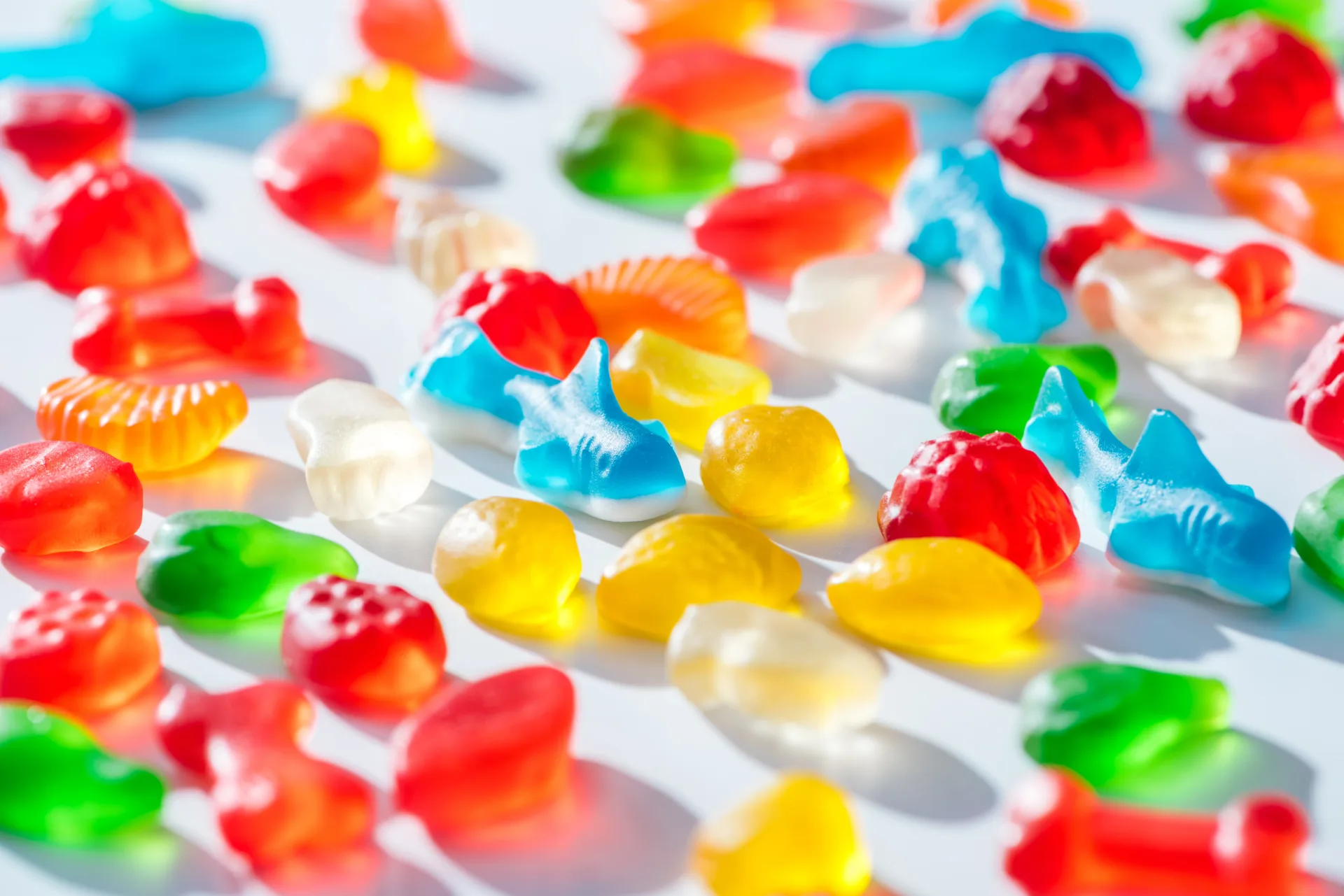Colorful gummy candies scattered on white surface.
