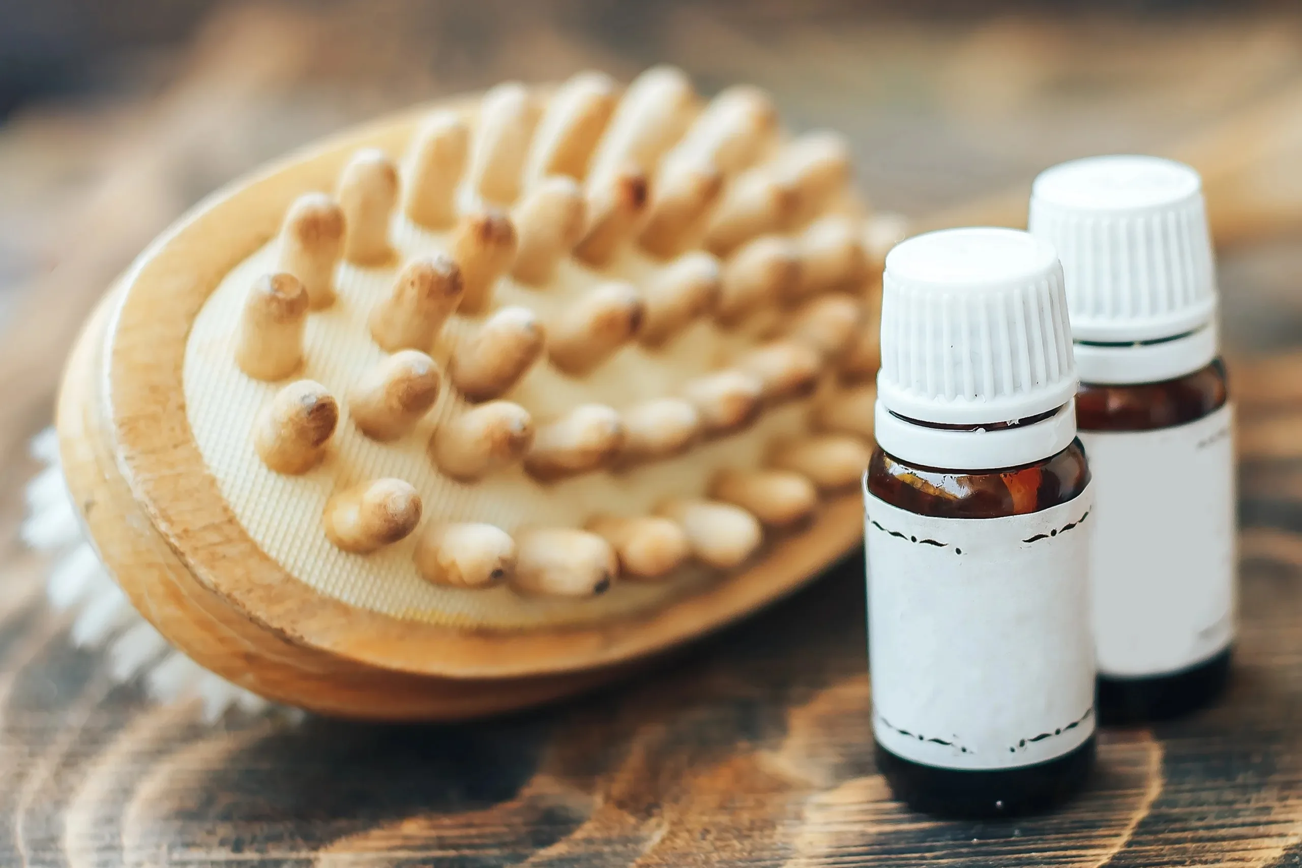 Wooden massage brush and essential oils bottles