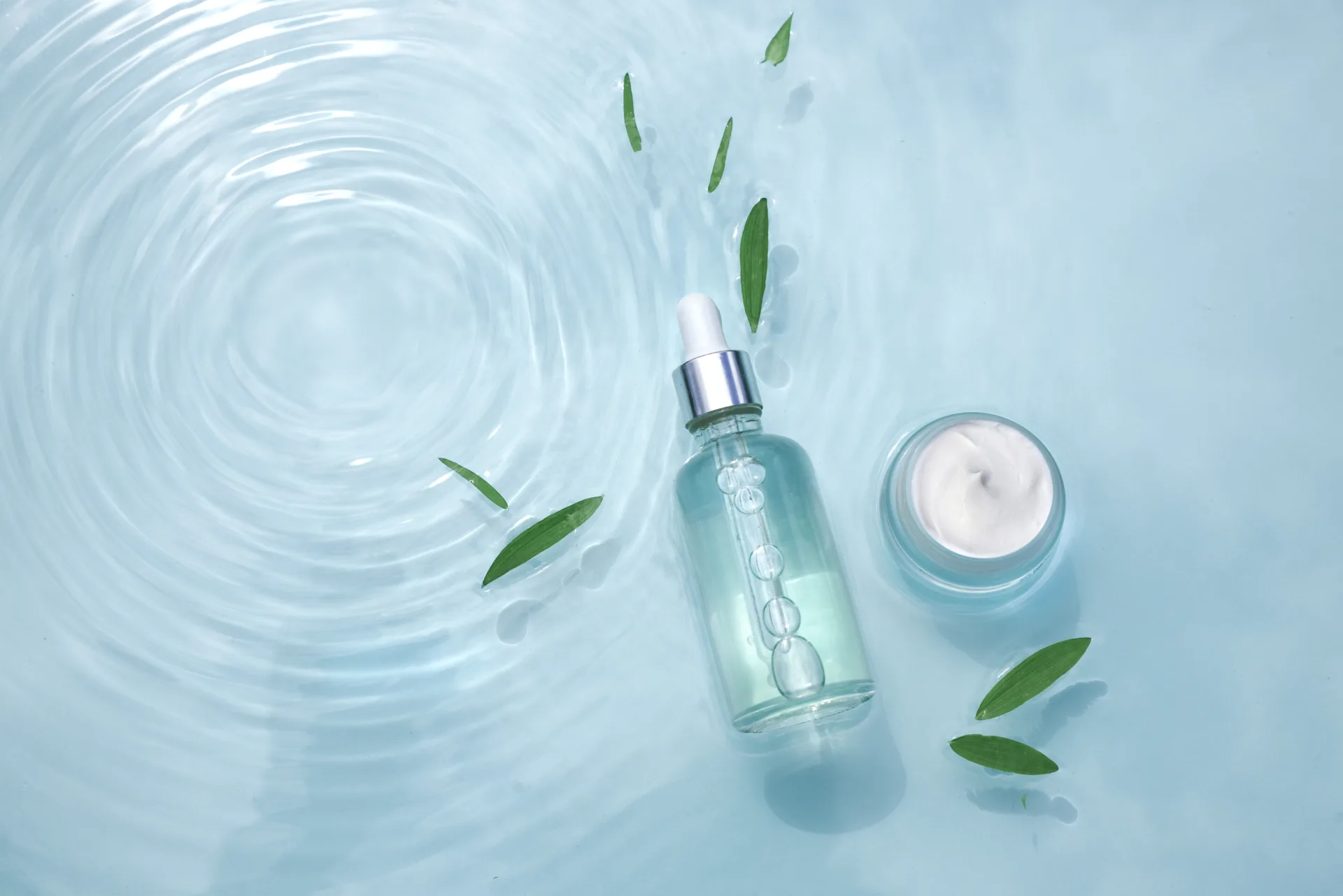 Serum and cream in water with green leaves