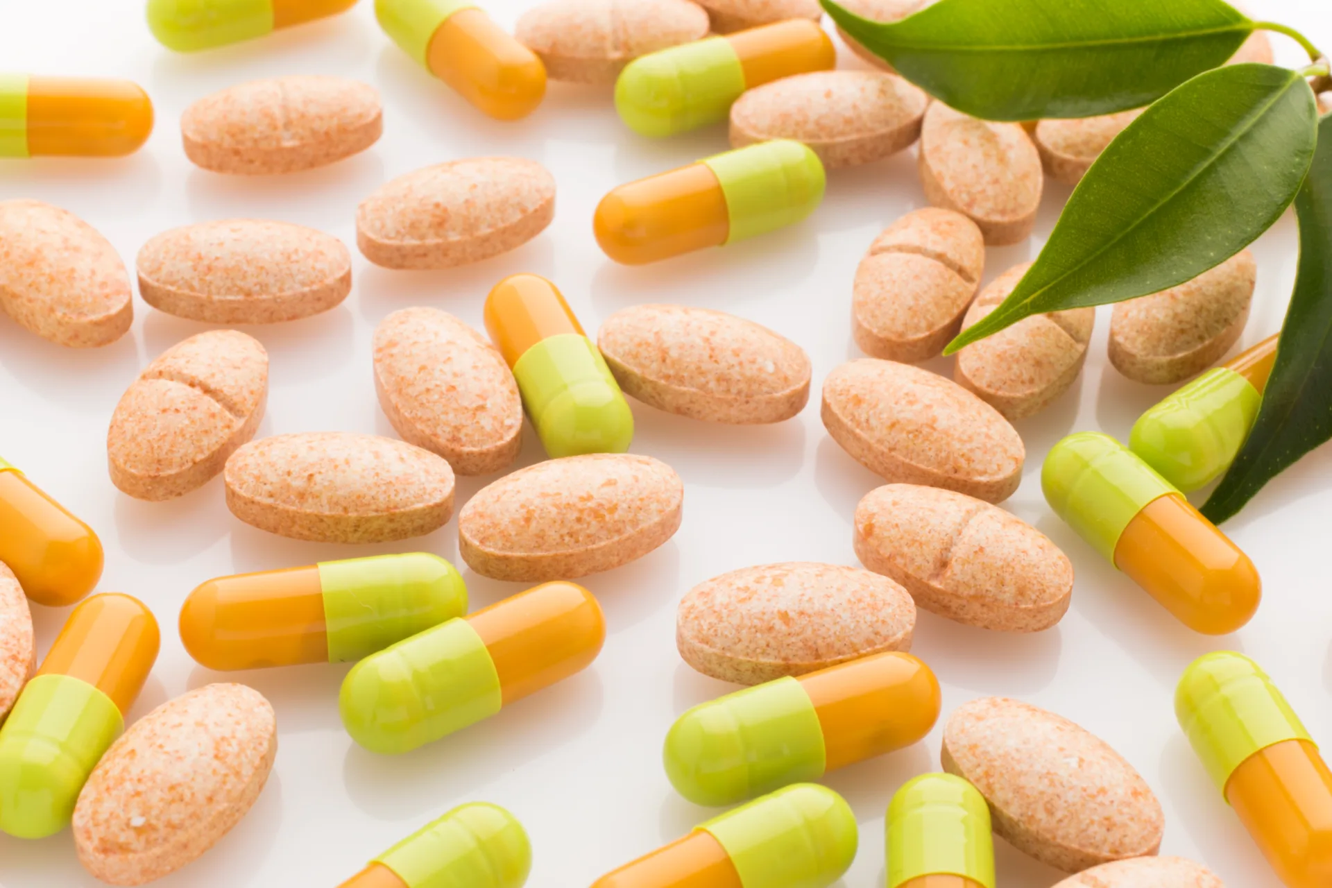 Assorted pills and capsules with green leaves