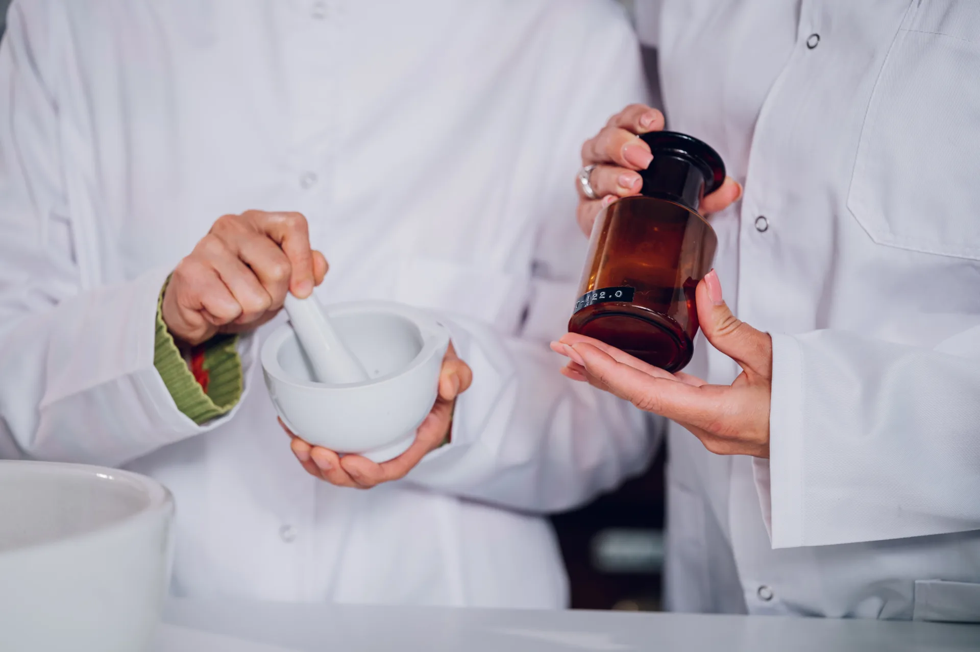 Scientists preparing compound with mortar and pestle.