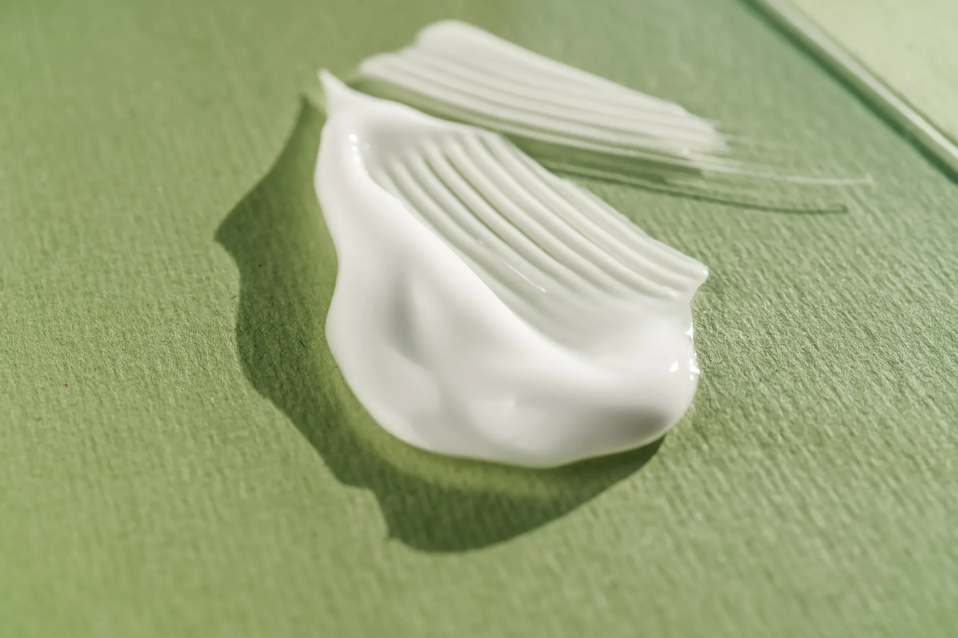 Close-up of white cream on green background.