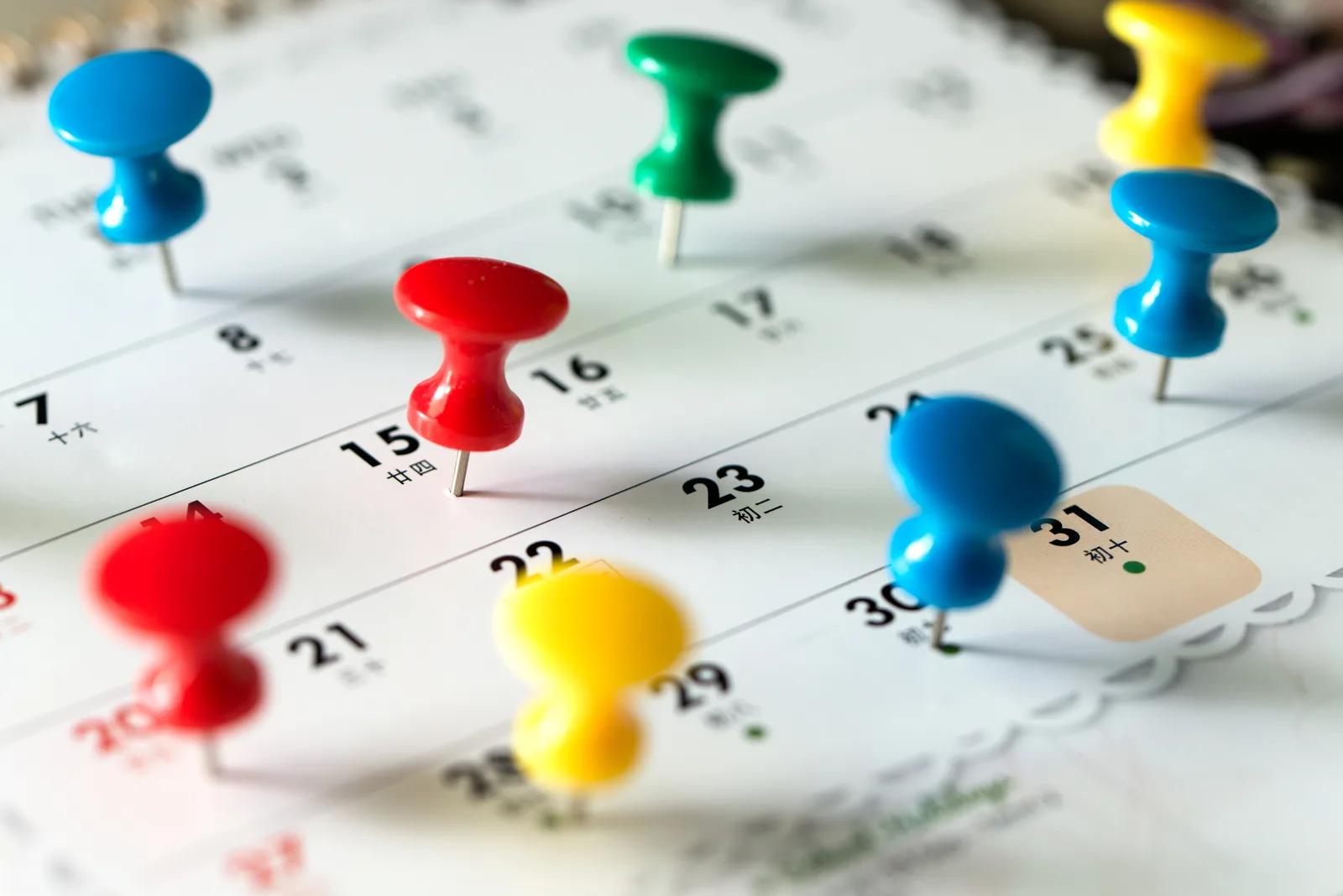 Colorful push pins on a calendar page.