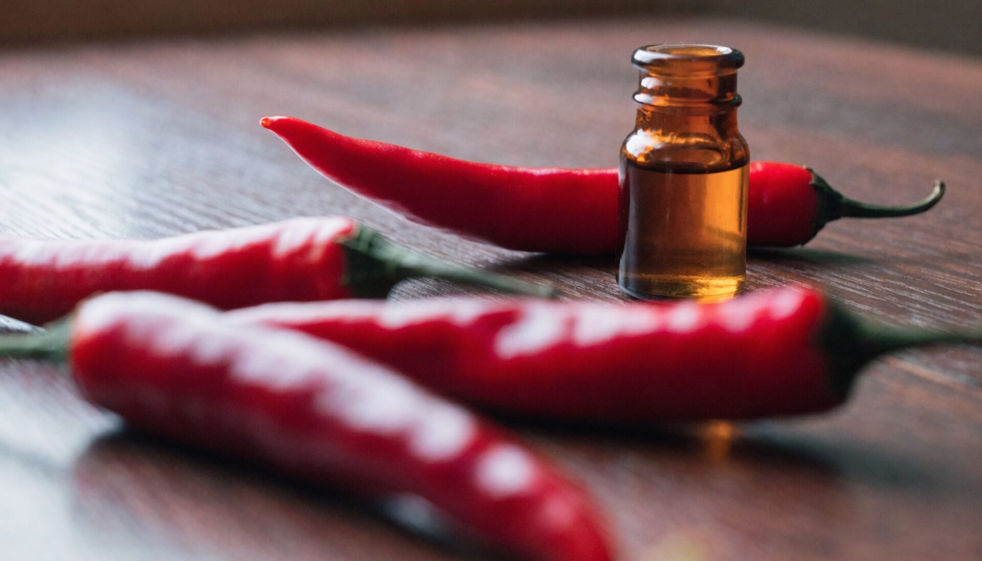 Red chili peppers and capsicum oil extract bottle, editorial food photography