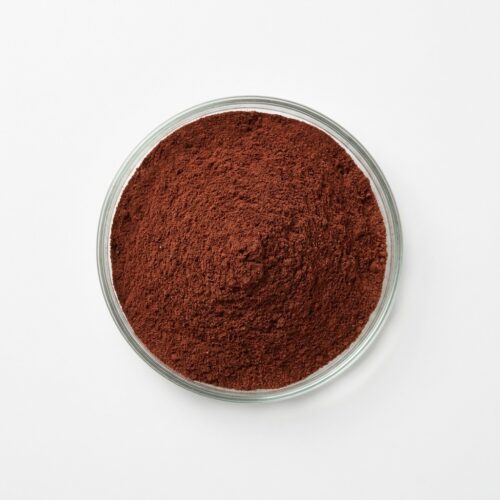 Rich brown date fruit powder in a glass petri dish