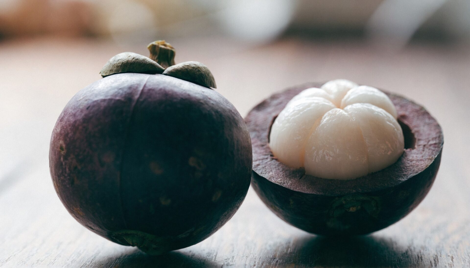 Whole and halved mangosteen fruit showing purple rind and white flesh
