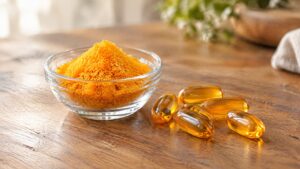 Coenzyme Q10 (CoQ10): orange-yellow powder beside softgel capsules